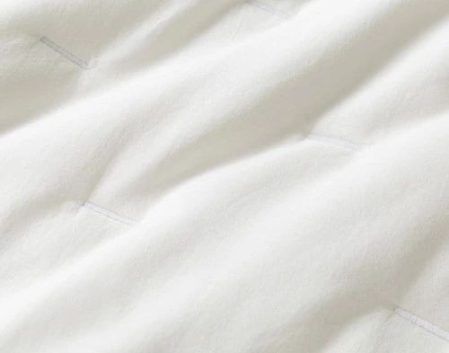 Close-up on the scattered horizontal line stitching on the solid white surface of our Alessia White Quilt Set.