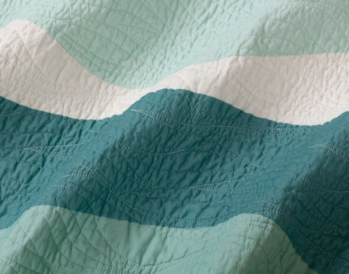 Close-up view of our Ocean Waves Cotton Quilt Set to show its flowing stitched lines and colours.