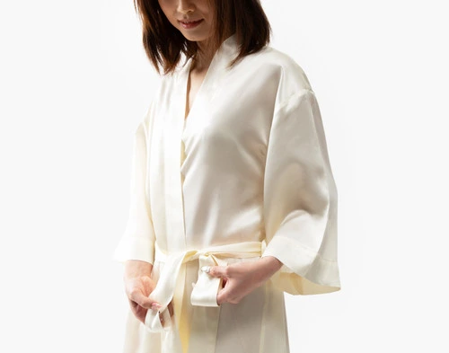 Close-up of our Snow Silk Kimono Robe being worn by a young woman adjusting the coordinating belt.