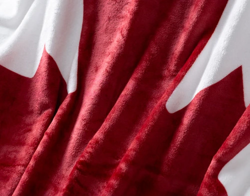 Close-up on the subtle shimmer of the red maple leaf on our Canada Flag Fleece Throw.