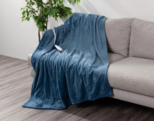 Angled view of our Teal Blue Plush Electric Heated Throw draped over a grey couch in a casual living room.