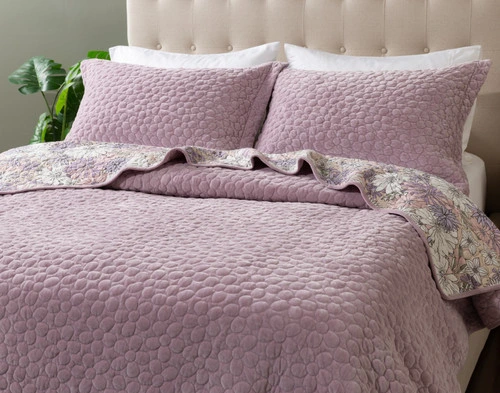 Angled view of our Lavender Daisy Chain Quilt Set dressed over a queen bed.