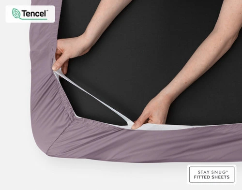 Bottom side of our BeechBliss TENCEL™ Modal Fitted Sheet in Purple Haze with two hands showing the Snug Fit Technology holding it tightly on the mattress.