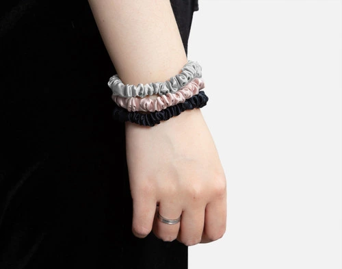 Close-up on a thin wrist wearing our Blush, Black, and Silver scrunchies like a watch.