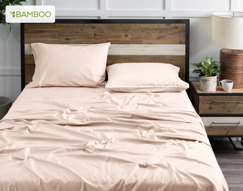 Front view of our Bamboo Cotton Sheet Set in Rosemist dressed over a wooden bed in a white bedroom.