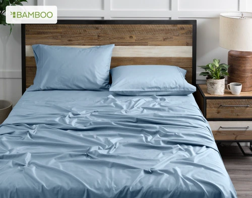 Front view of our Bamboo Cotton Sheet Set in Mistral Blue dressed over a wooden bed in a white bedroom.