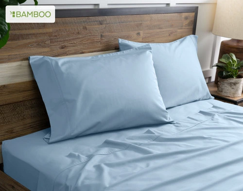 Two of our Bamboo Cotton Pillowcases in Mistral Blue resting on a wooden bed with coordinating sheets.