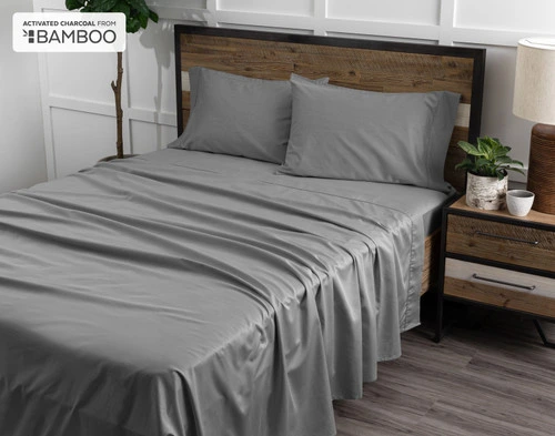 Angled view of our Deep Charcoal Bamboo Cotton Sheet Set to show its flat sheet, fitted sheet, and pillowcases spread over a queen bed.