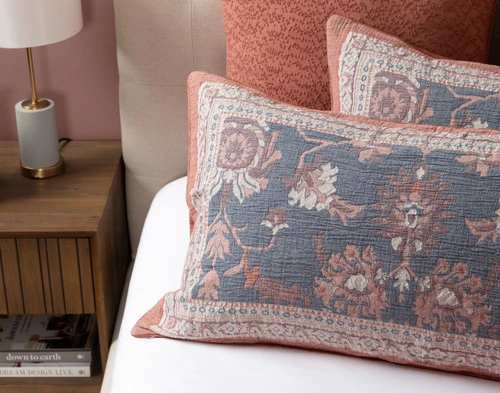 Angled view of our two Mahara Pillow Shams resting on a half-dressed white bed.