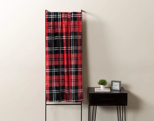 Front view of our Carmine Plaid Throw draped over a rack leaning against a cream white wall.