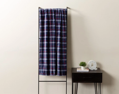 Front view of our Royal Plaid Throw draped over a rack leaning against a cream white wall.