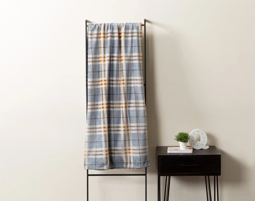 Front view of our Forbes Plaid Throw draped over a rack leaning against a cream white wall.