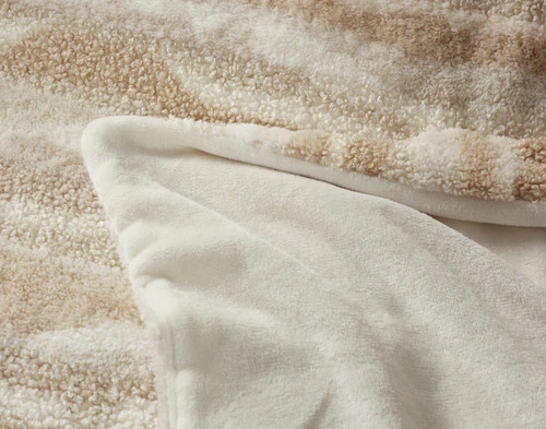 Folded corner of our Natural Terra Nova Throw to show its off-white plush-like backing.