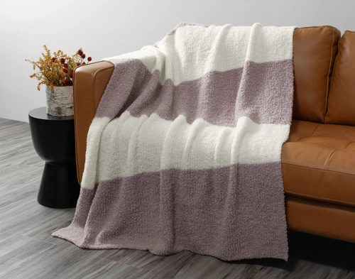 Front view of our Ash & Cream Wooly Knit Throw draped over a brown couch.