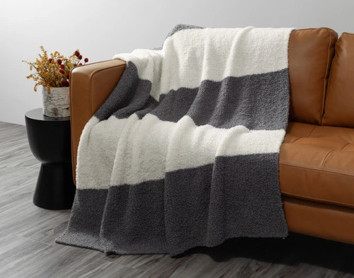 Front view of our Grey & Cream Wooly Knit Throw draped over a brown couch.