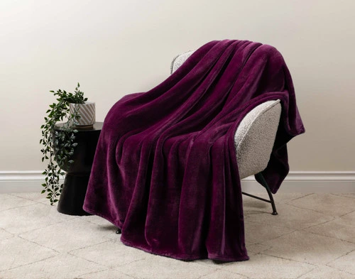 Our Velveteen Throw in Purple Rain draped over a beige chair in a white living room.