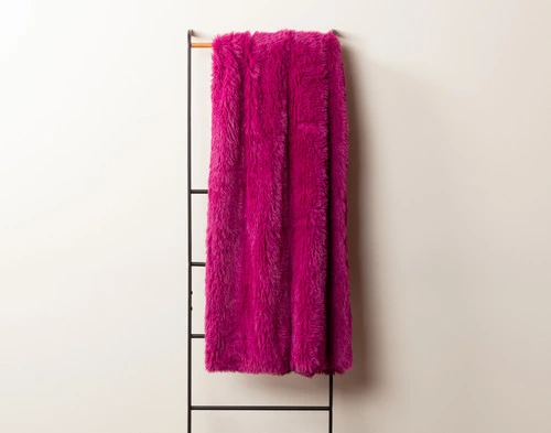 Front view of our Fuchsia Soft Mink Throw draped over a tall rack against an empty white wall.