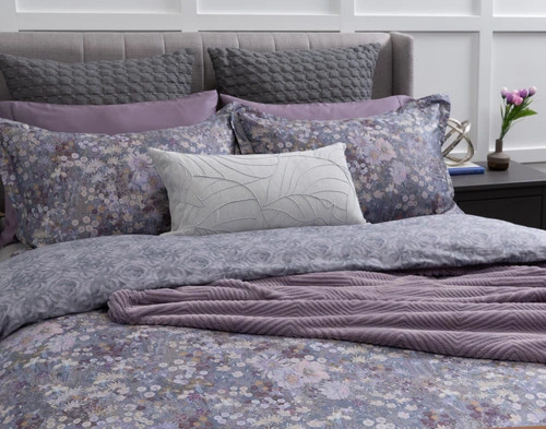 Closer view of our Novella Duvet Cover dressed simply with grey cushions and a purple throw blanket over a queen bed.