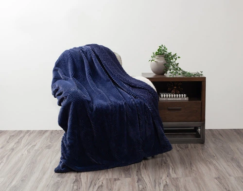 Front view of our Navy Chevron Etch Throw draped over a small chair in a simple living room.