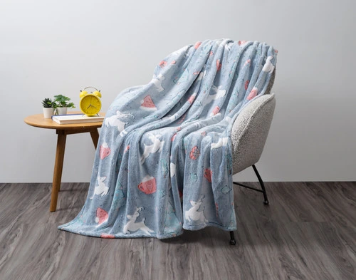 Our Sweet Treats Glow in the Dark Fleece Throw draped over an armchair in an empty grey living room.