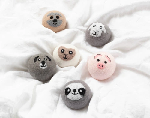 Top view of all our Embroidered Wool Dryer Balls sitting scattered over a solid white blanket.