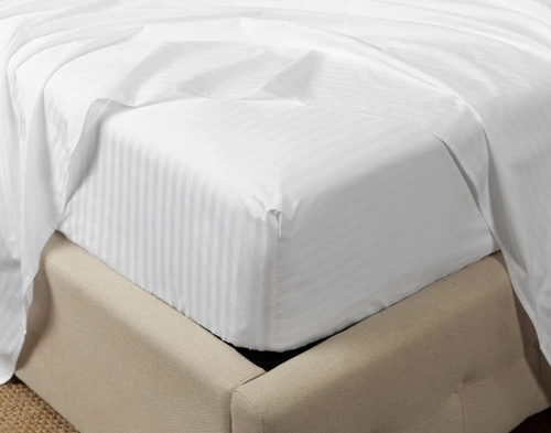 Close-up of the fitted sheet fitted over the corner of a mattress from our Striped White Cotton Percale Blend Sheet Set.