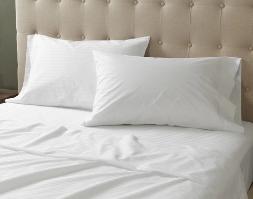 Closer view of our Striped White Cotton Percale Blend Pillowcases sitting at the headboard of a plain queen bed.