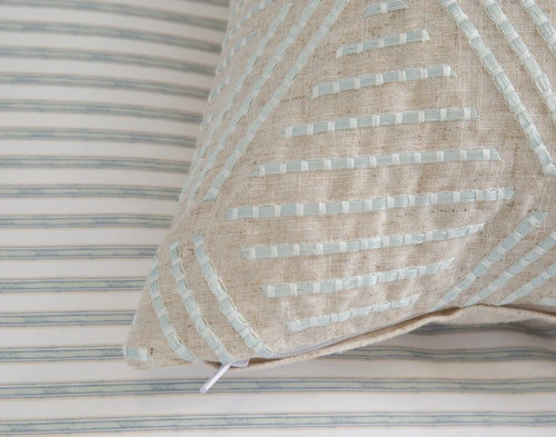 Close up of the corner of our Bayview Square Cushion Cover laying atop the reverse side of our Bayview Duvet Cover.