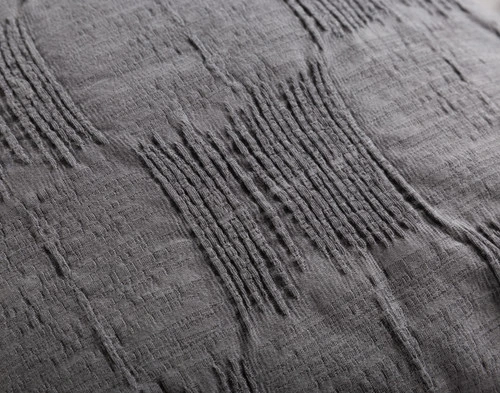 Close-up of one a woven grey patch on the surface of our Mazama Square Cushion Cover.