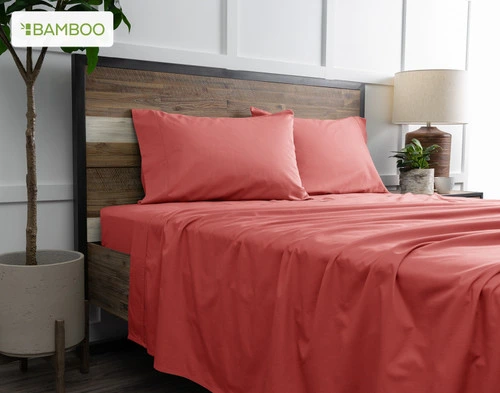 Angled view from below of our Bamboo Cotton Sheet Set in Huckleberry, dressed over a wooden bed in a white plant-filled bedroom.