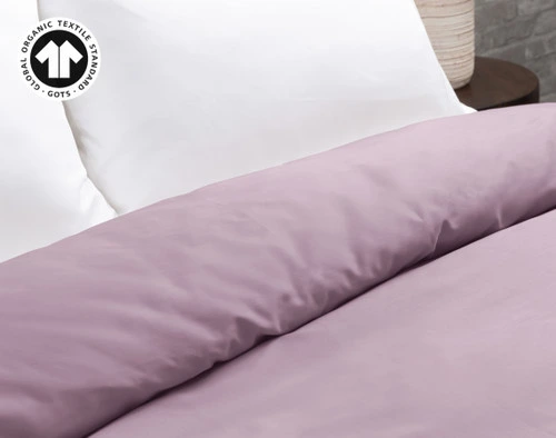 Our Organic Cotton Duvet Cover in Amethyst Purple at the head of a bed with white pillows.