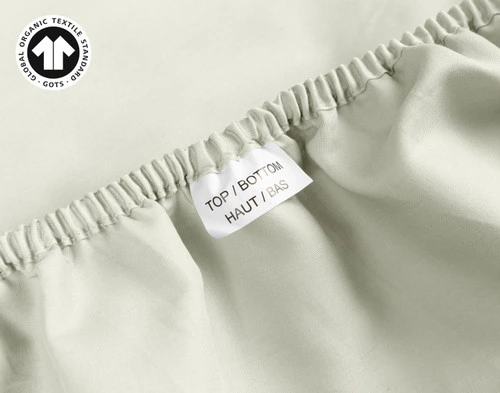 Close-up on a tag reading Top & Bottom on the edge of our Organic Cotton Fitted Sheet in Sagebrush.