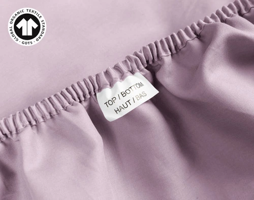 Close-up on a tag reading Top & Bottom on the edge of our Organic Cotton Fitted Sheet in Amethyst.