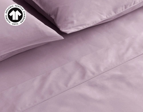 Close-up on our Organic Cotton Sheet Set in Amethyst to show its pillows, flat sheet, and fitted sheet neatly made.