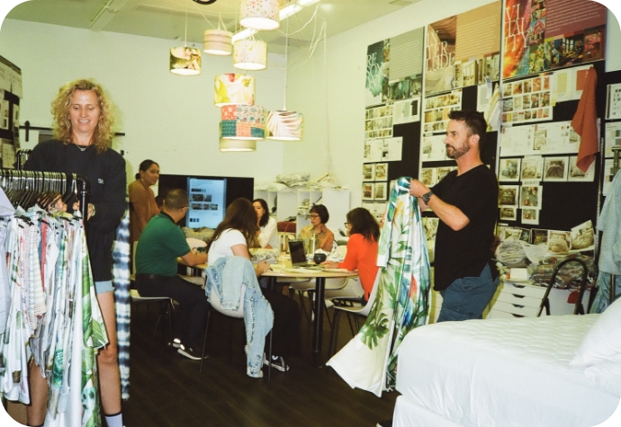 The QE Home design studio with the product team collaborating, showcasing fabric samples, and discussing ideas. The space is filled with mood boards, textiles, and vibrant decor.