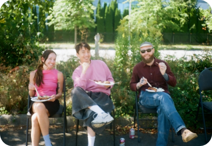 Members of our Creative Team sit at a table enjoying their lunch while posing for the camera.