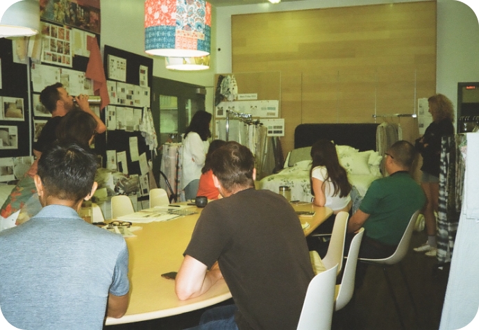 The QE Home product team gathers around a table, reviewing product samples on a bed.