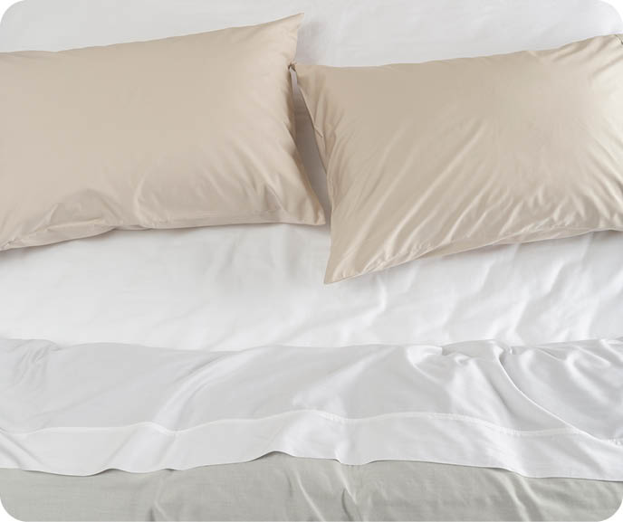 A bed with crisp white BeechBliss sheets and two pillows dressed with our Eucalyptus Luxe TENCEL™ Lyocell pillowcases in Ash.