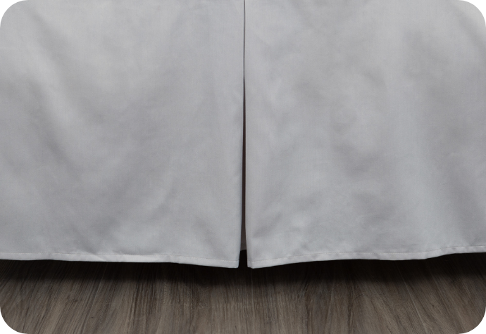 Close up of a grey bedskirt on a bed.