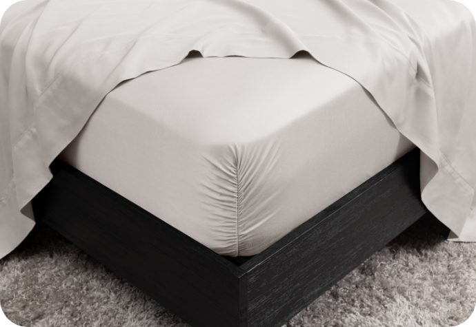 A fitted sheet tucked snugly under the corner of a mattress.
