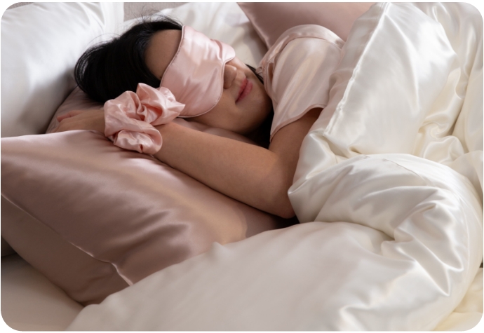 Woman asleep in atop Mulberry Silk Pillowcases with Mulberry Silk sleep accessories.