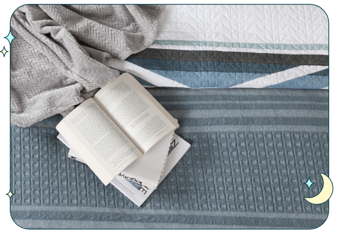 Top view of an open book sitting on a textured blue and grey bed.