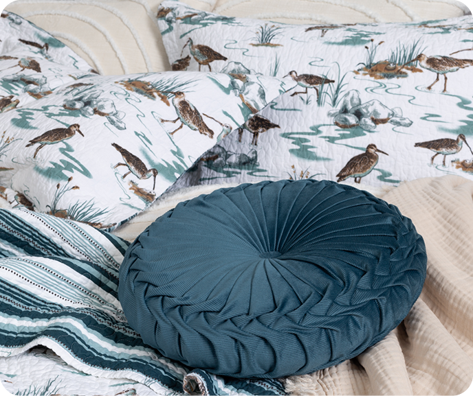 Our Sandpiper Cotton Quilt Set styled with our Pin-Tuck Round Corduroy Cushion in Ocean and Muslin Gauze Throw in Natural.