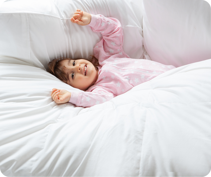A child lying in bed surrounded by a fluffy white duvet.